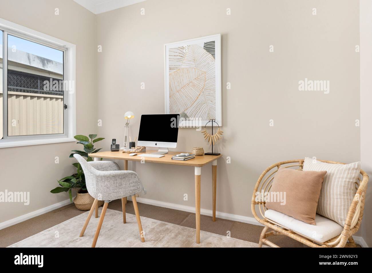 Una sala studio con un computer collocato su una scrivania di legno vicino a una finestra Foto Stock
