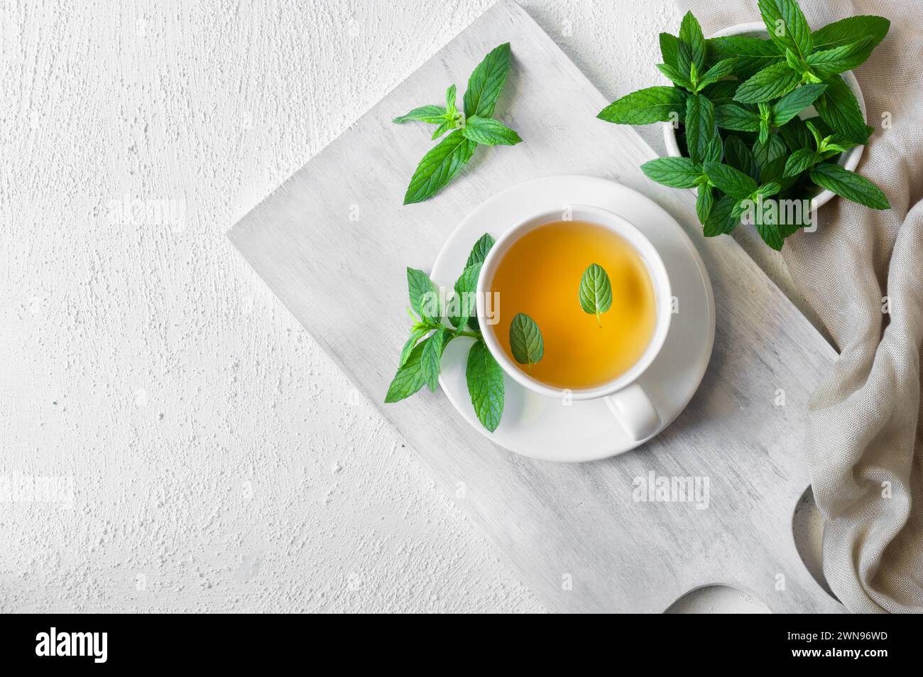 Tazza di tè alla menta con foglie di menta verde fresca su tavola rustica, sana bevanda calda a base di erbe Foto Stock