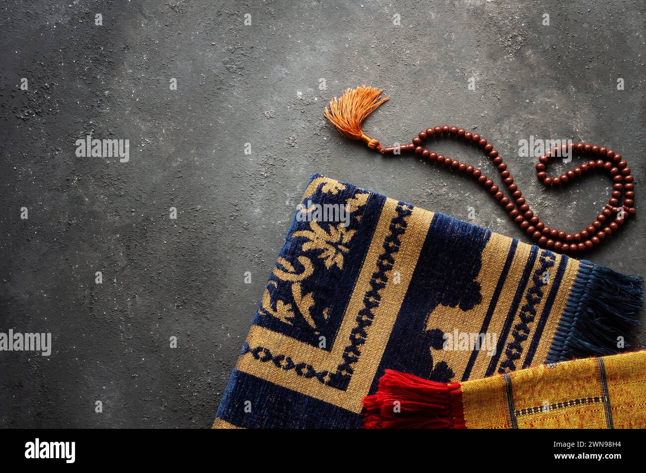 Tappeto di preghiera e rosario su sfondo di pietra per il culto nel mese del Ramadan Foto Stock