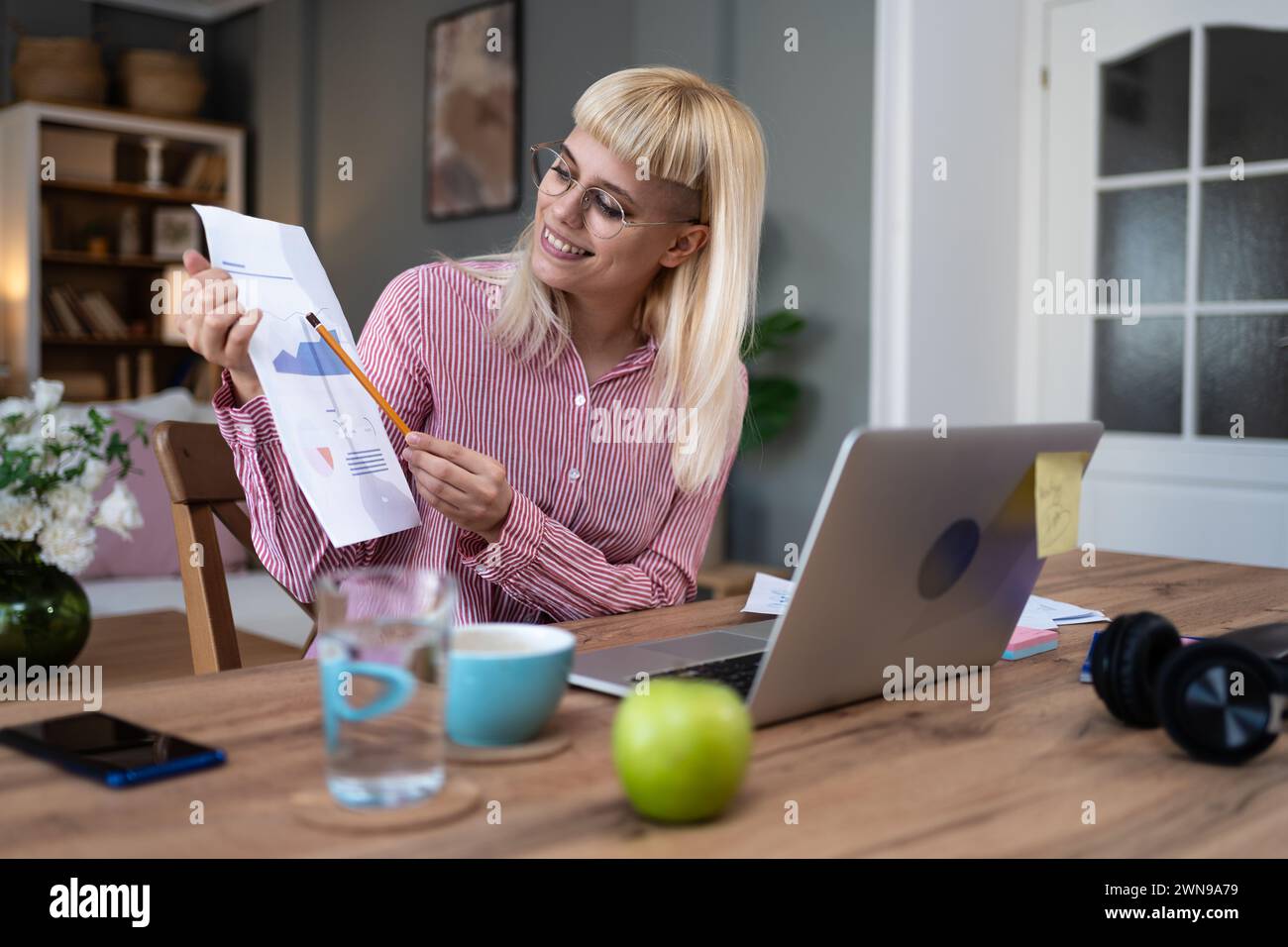 Giovane donna d'affari freelance espatriata esperta di marketing finanziario e digitale che lavora a casa in ufficio e che ha videochiamata su un computer portatile Foto Stock