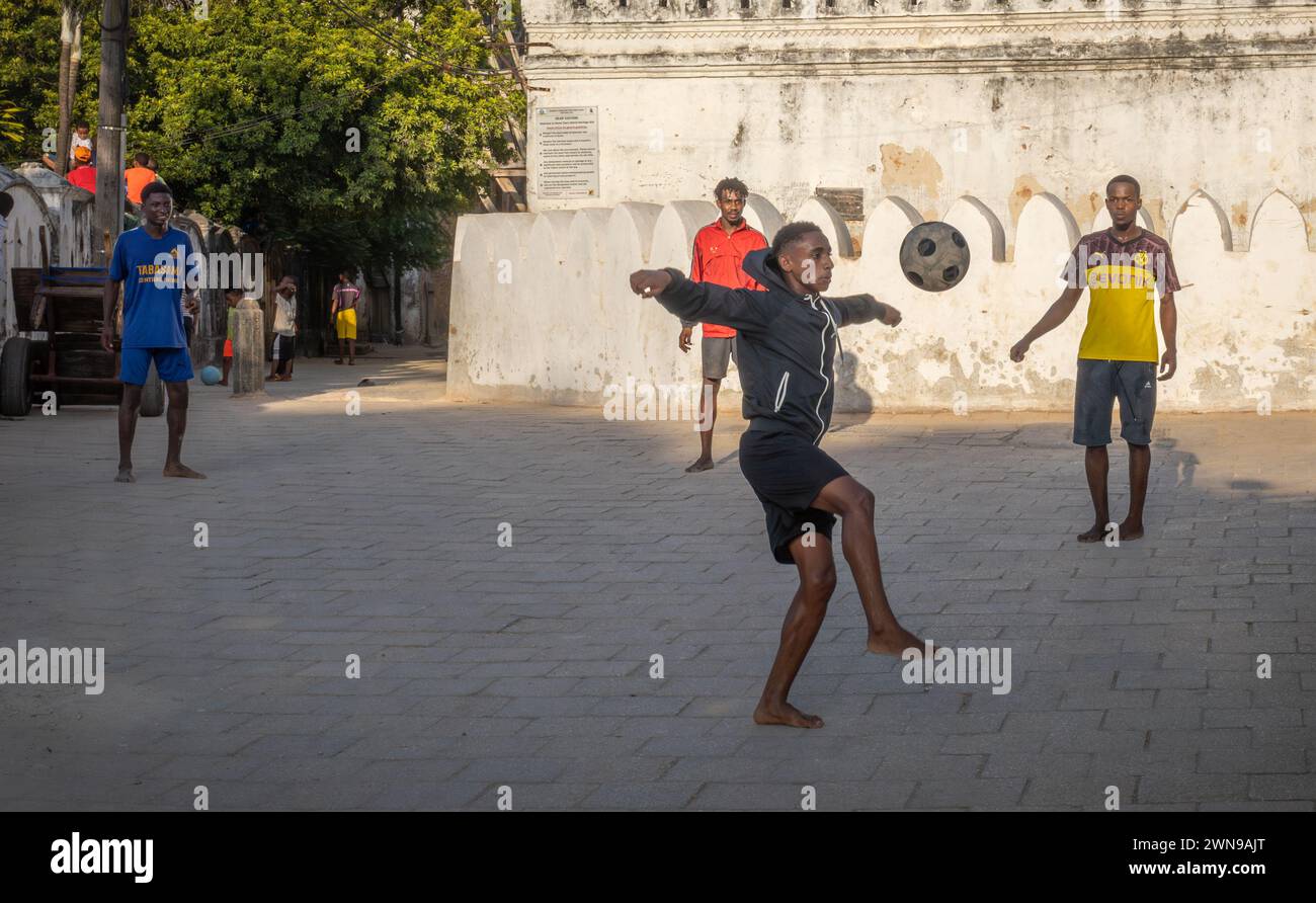 Quattro giovani giocano a calcio in strada a Stone Town, Zanzibar, Tanzania Foto Stock