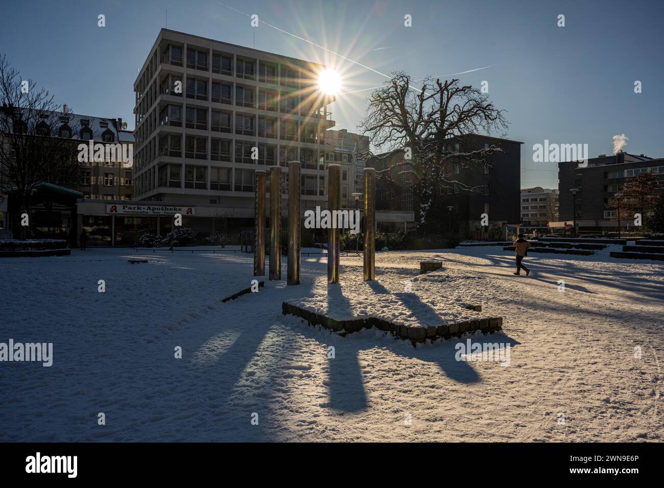 Raggi di sole che brillano attraverso un edificio di una città, in inverno, persone che camminano sullo sfondo, Deweerthscher Garten, Elberfeld, Wuppertal, Bergisches Foto Stock
