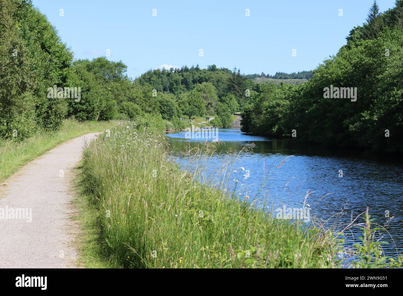 Canale di campagna e sentiero per la città in estate Foto Stock