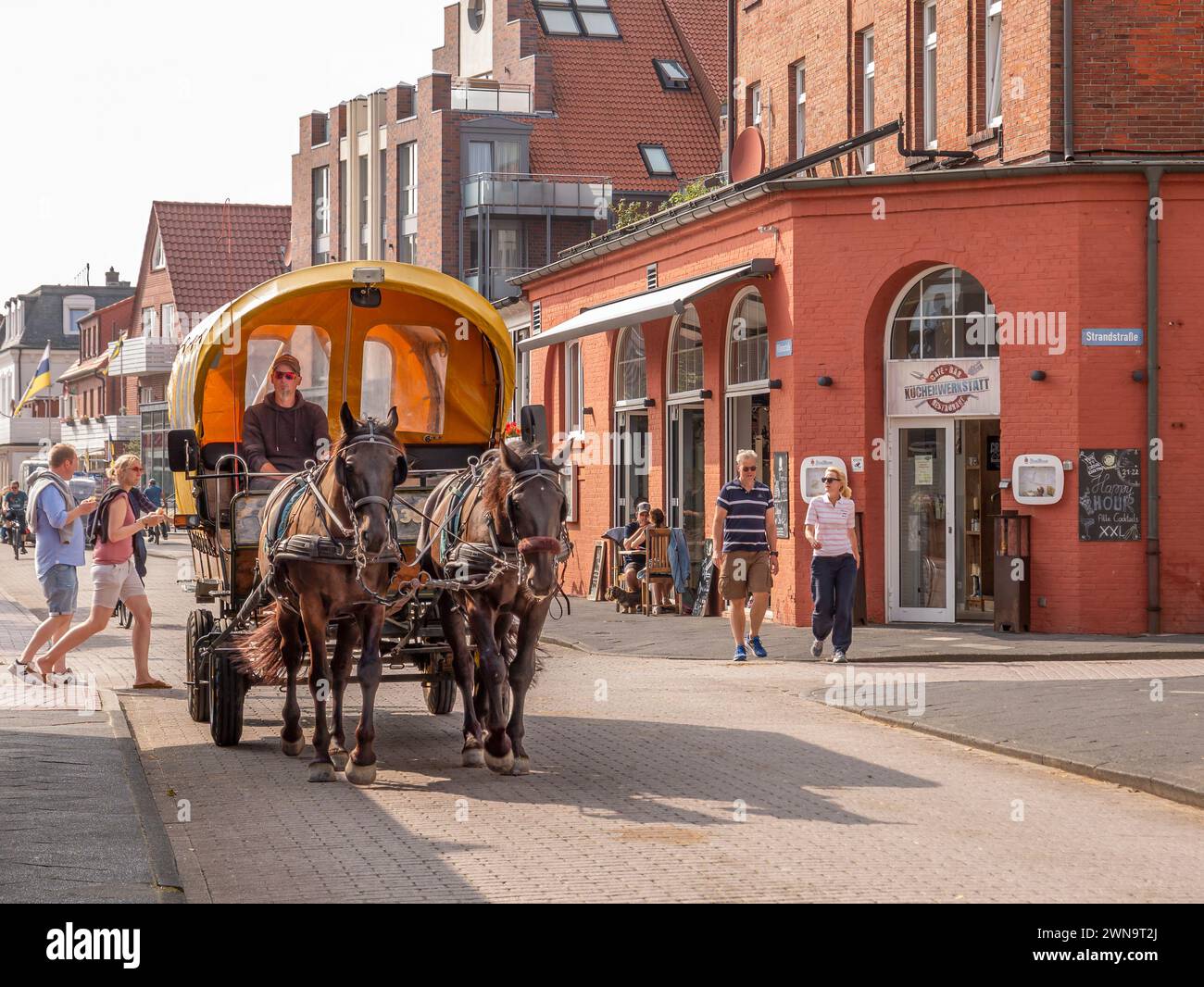 Carrozza trainata da cavalli e persone che camminano nella città dell'isola della Frisia orientale Juist, bassa Sassonia, Germania Foto Stock