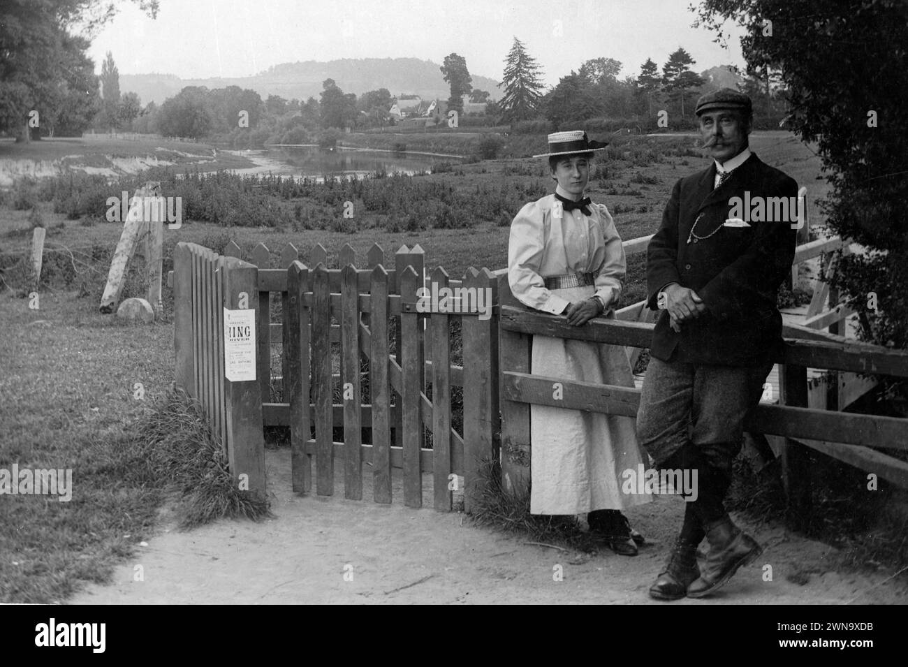 1897 Fotografia storica in bianco e nero di Mr & Miss Richards in piedi presso un cancello e recinto di legno vicino al fiume Wye, Hereford, Herefordshire, Inghilterra, Regno Unito Foto Stock