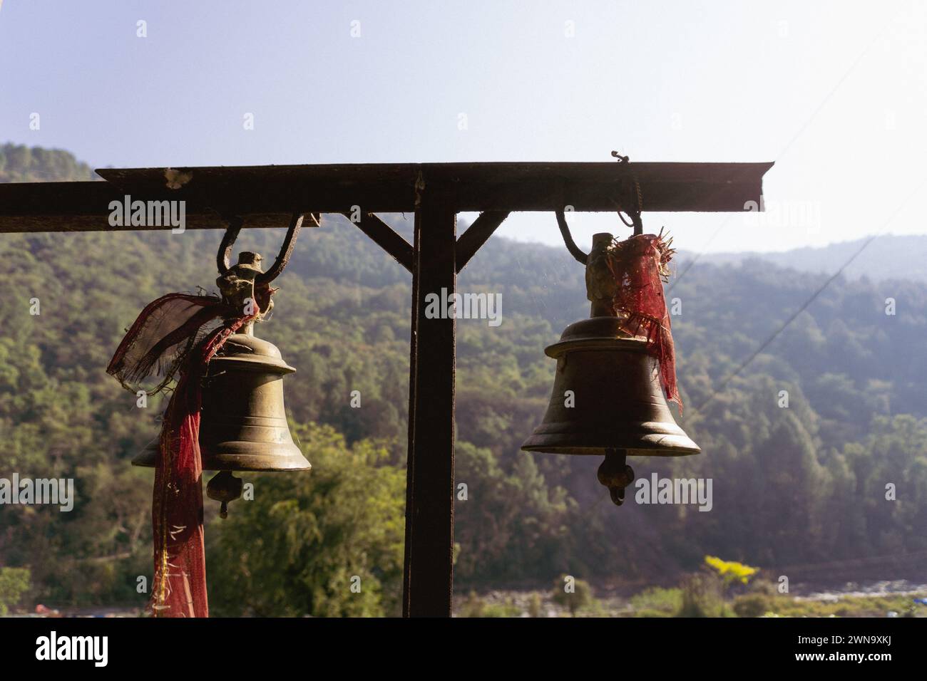 Campane di bronzo con panni rossi: Simbolismo spirituale al tempio Tarkeshwar Mahadev, Uttarakhand, India Foto Stock
