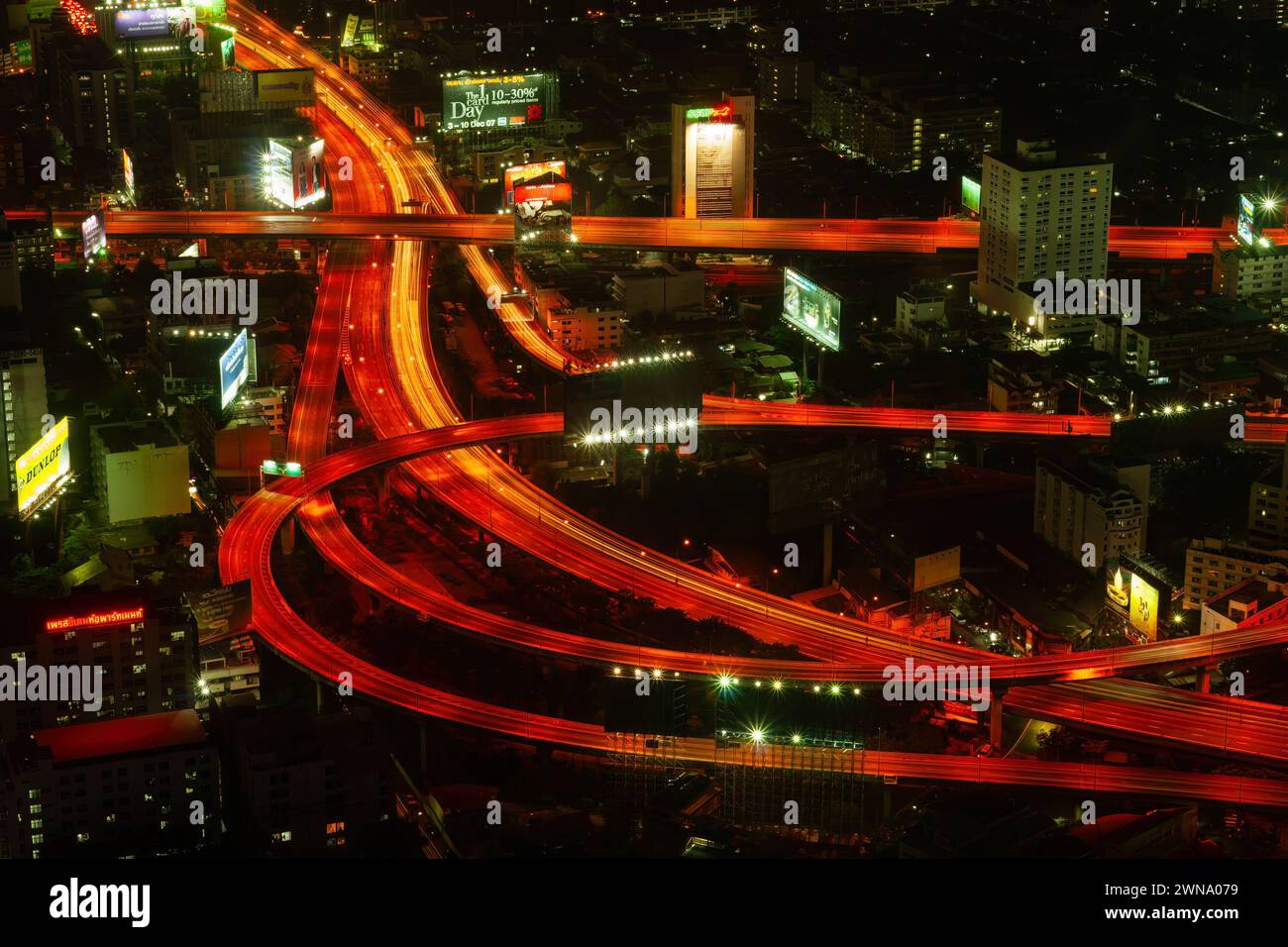 Vista aerea della superstrada di Bangkok e dell'autostrada di notte nella capitale della Thailandia. Strade tortuose infrastrutture cittadine dall'alto, paesaggio urbano con g rosso Foto Stock