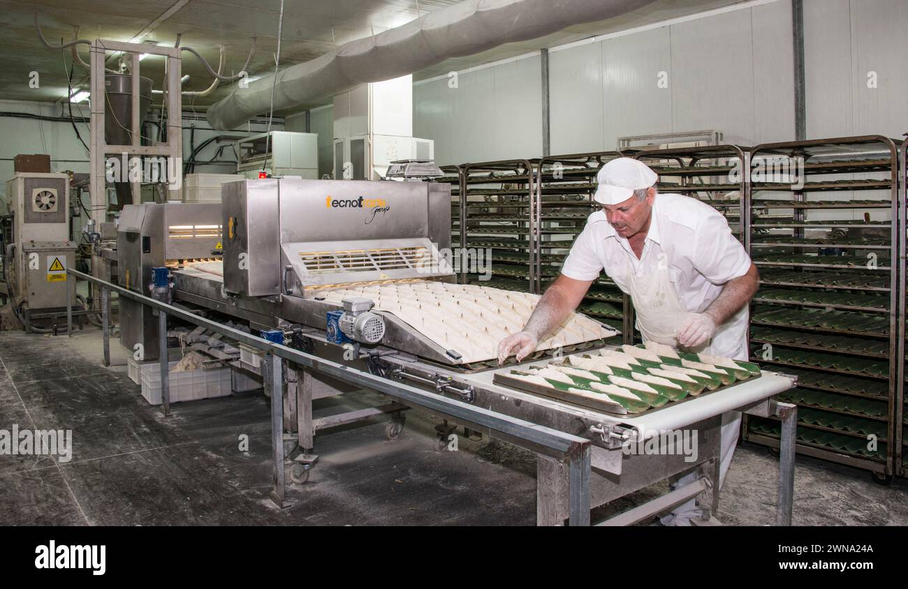Operatore e macchinari in un panificio industriale. Foto Stock