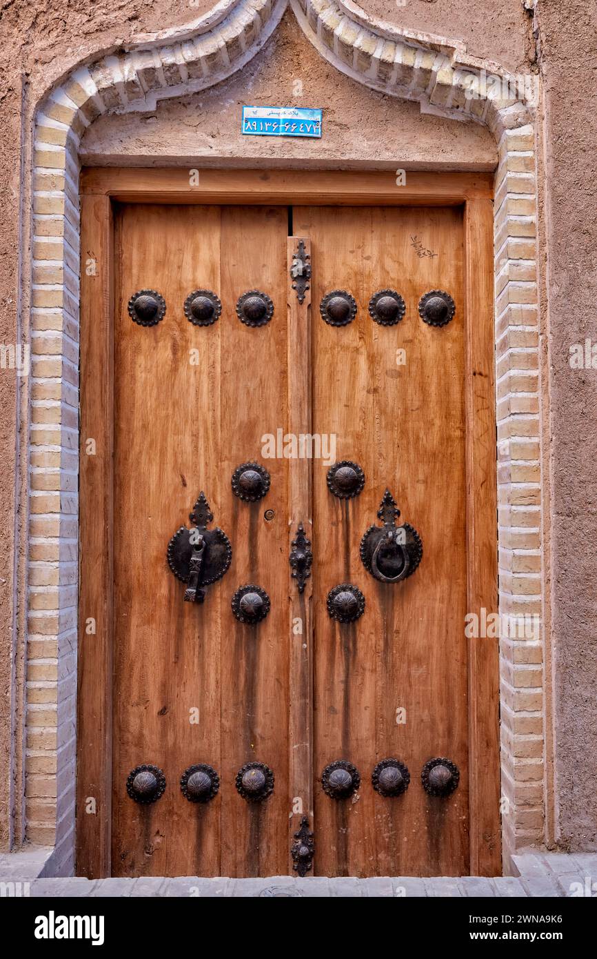 Porta d'ingresso tradizionale in legno con due battitori separati - barra in metallo per uomini e anello in metallo per donne. Yazd, Iran. Foto Stock