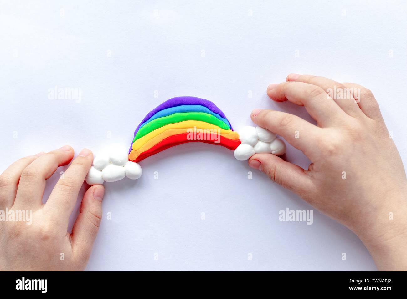 Il bambino scolpisce un arcobaleno e nuvole di plastilina. Creatività dei bambini Foto Stock