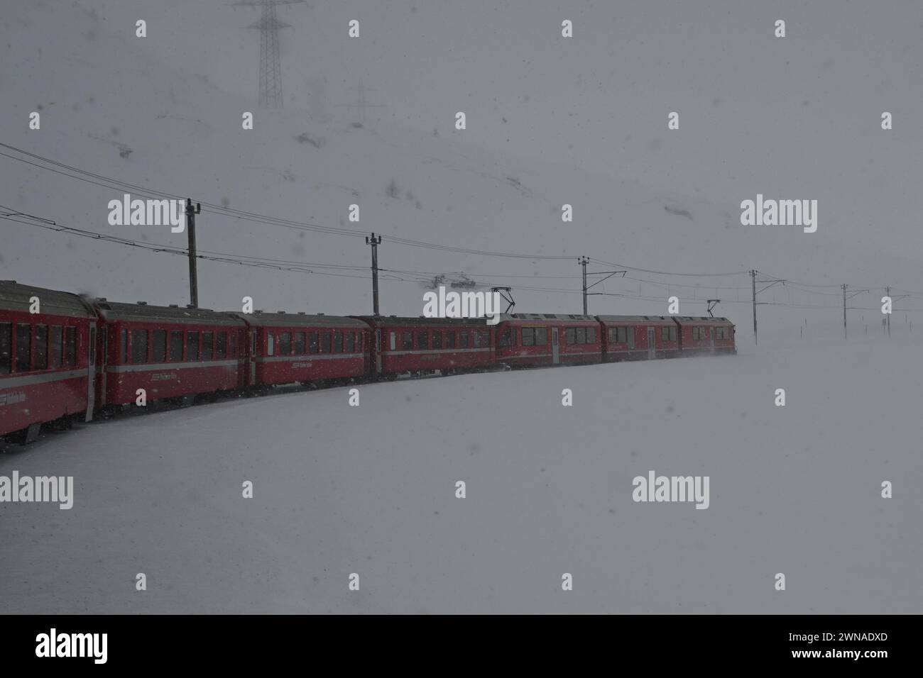 Il treno Bernina Express che attraversa le montagne sulla strada per l'Italia Foto Stock