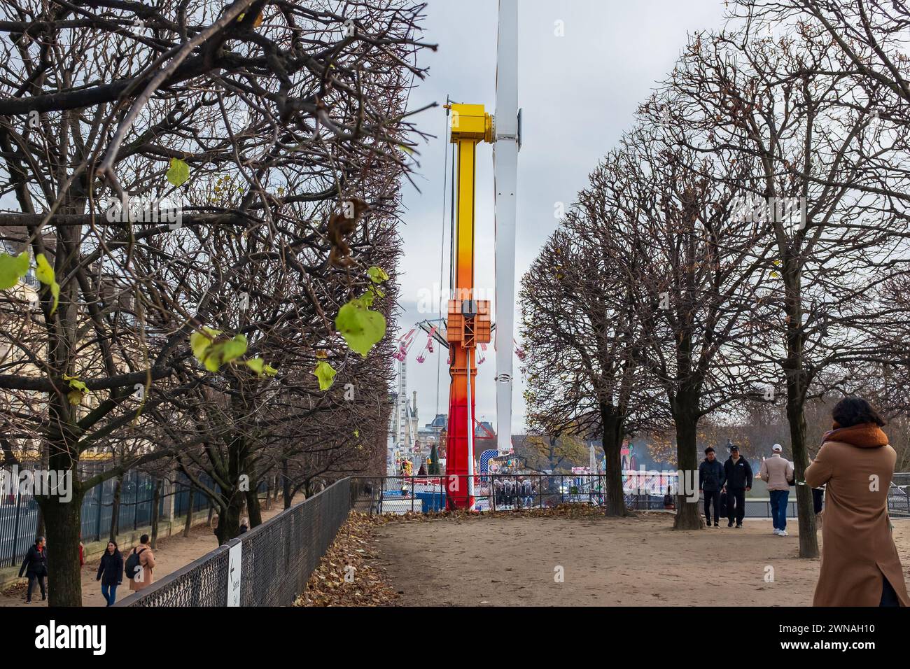 Parigi, Francia. Persone che si godono una passeggiata nei Jardin des Tuileries, con un giro di rilancio al parco divertimenti sullo sfondo Foto Stock