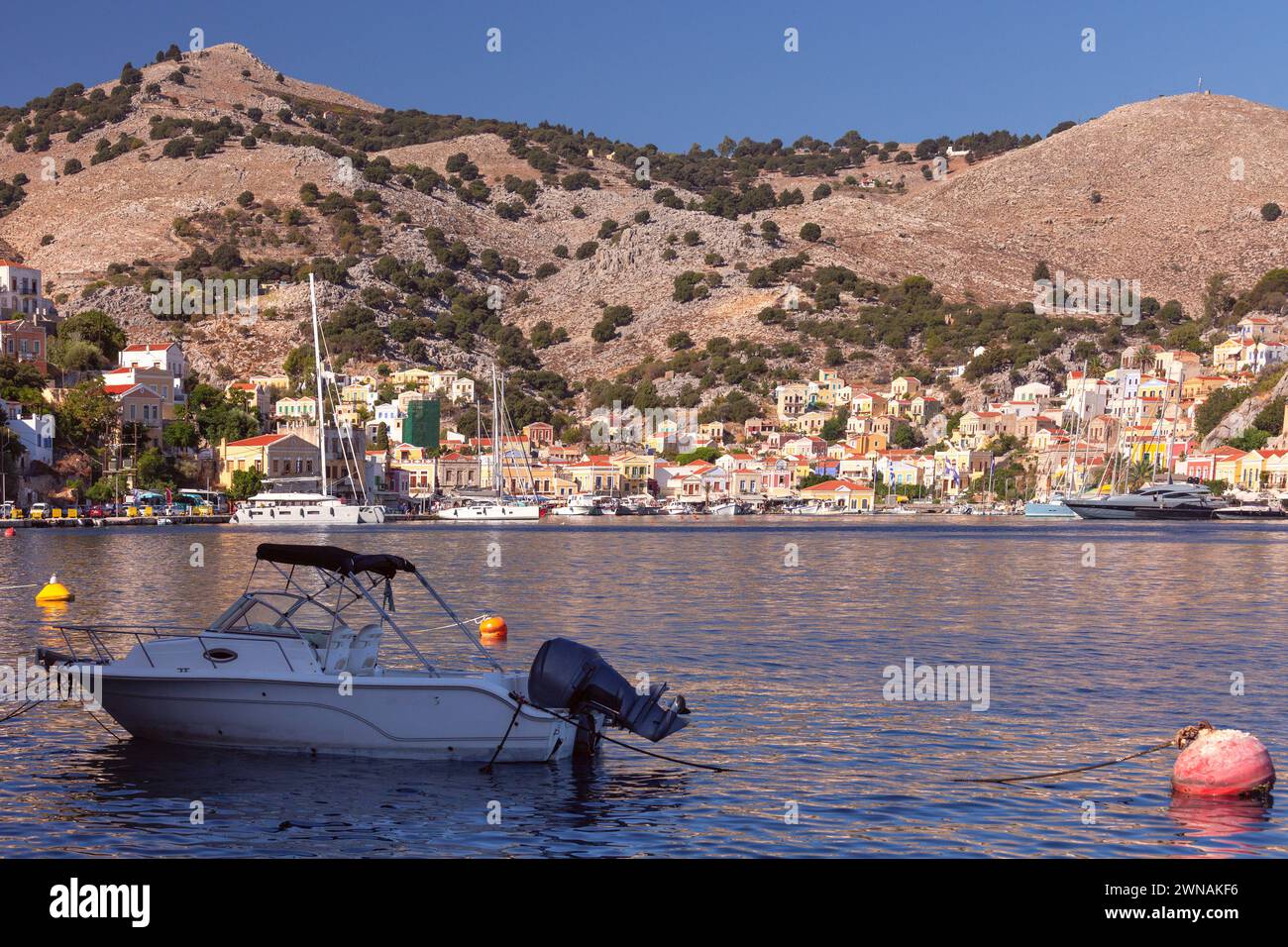 Vista delle case tradizionali colorate e delle barche da pesca nel villaggio di pescatori Symi in una giornata di sole. Grecia. Dodecaneso. Foto Stock