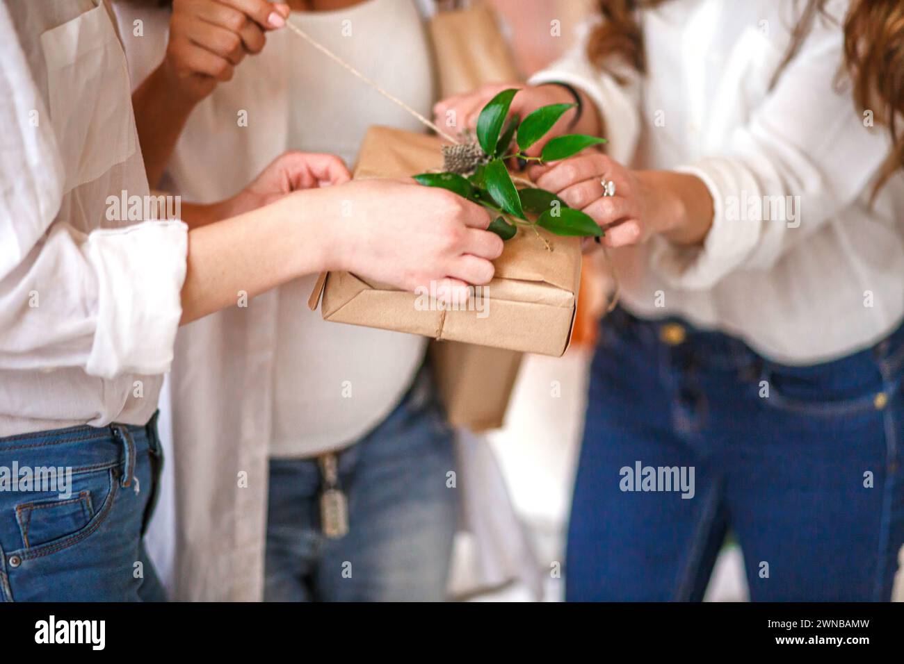 Gli ospiti svinano un nastro su un regalo fatto di carta kraft. Regali avvolti in carta kraft nelle mani degli ospiti alla festa Baby Shower regali decorati con Foto Stock