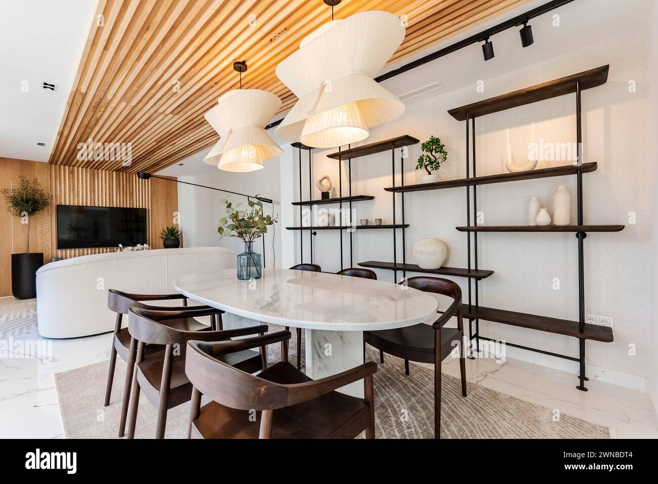 una lussuosa area soggiorno e sala da pranzo con televisore e divano accanto a un tavolo da pranzo in marmo nella villa mediterranea Foto Stock