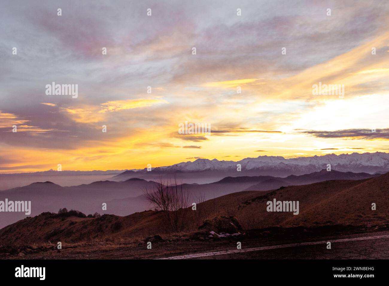 Tramonto in montagna. Cielo arancione e sfumature indaco. Monviso sullo sfondo e catena montuosa. Piemonte - Italia. Foto Stock