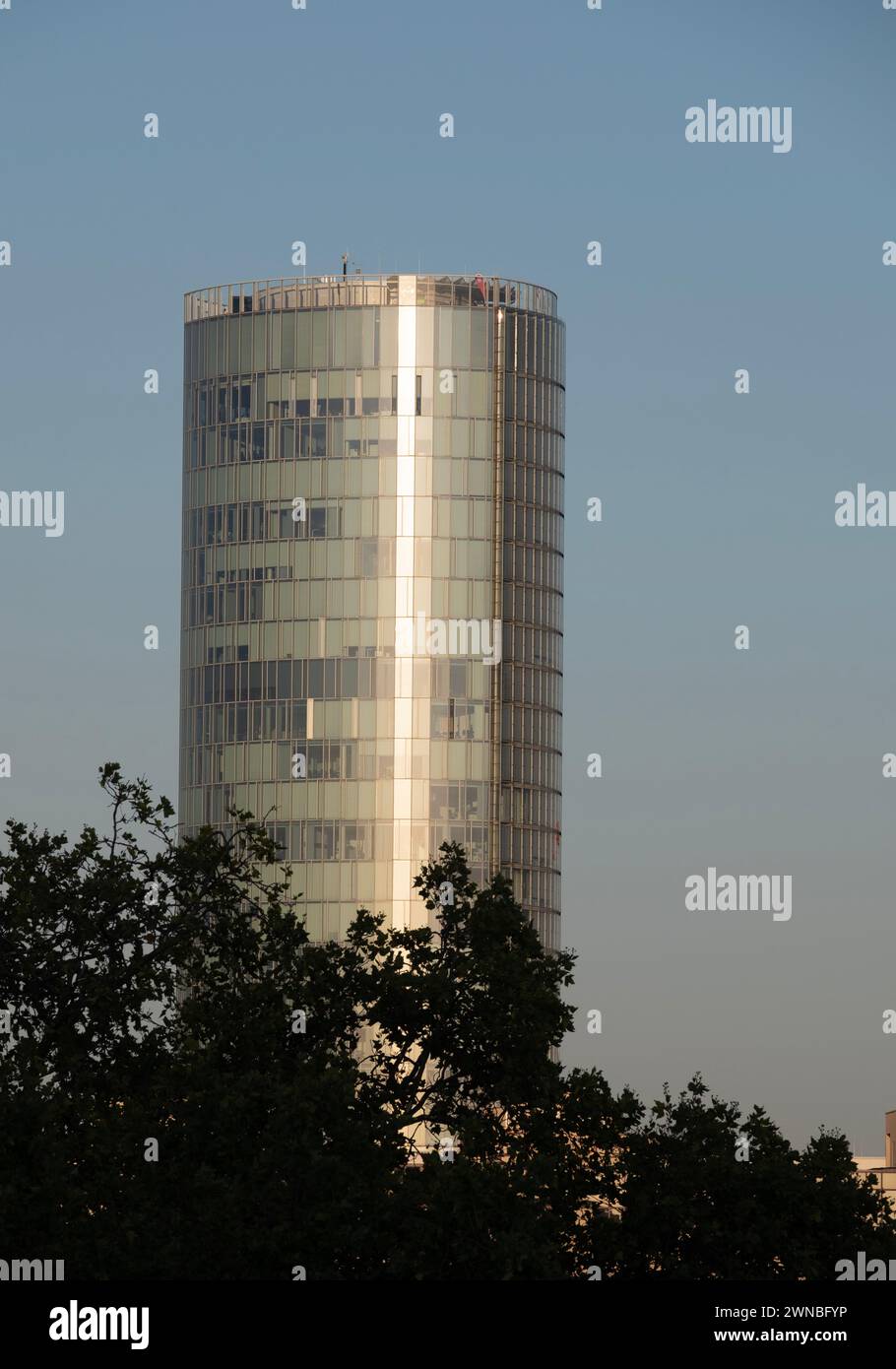 L'edificio del Triangolo di Colonia, formalmente noto come la Torre LVR, si affaccia su un cielo blu chiaro nel tardo pomeriggio, con alcuni alberi in primo piano. Foto Stock