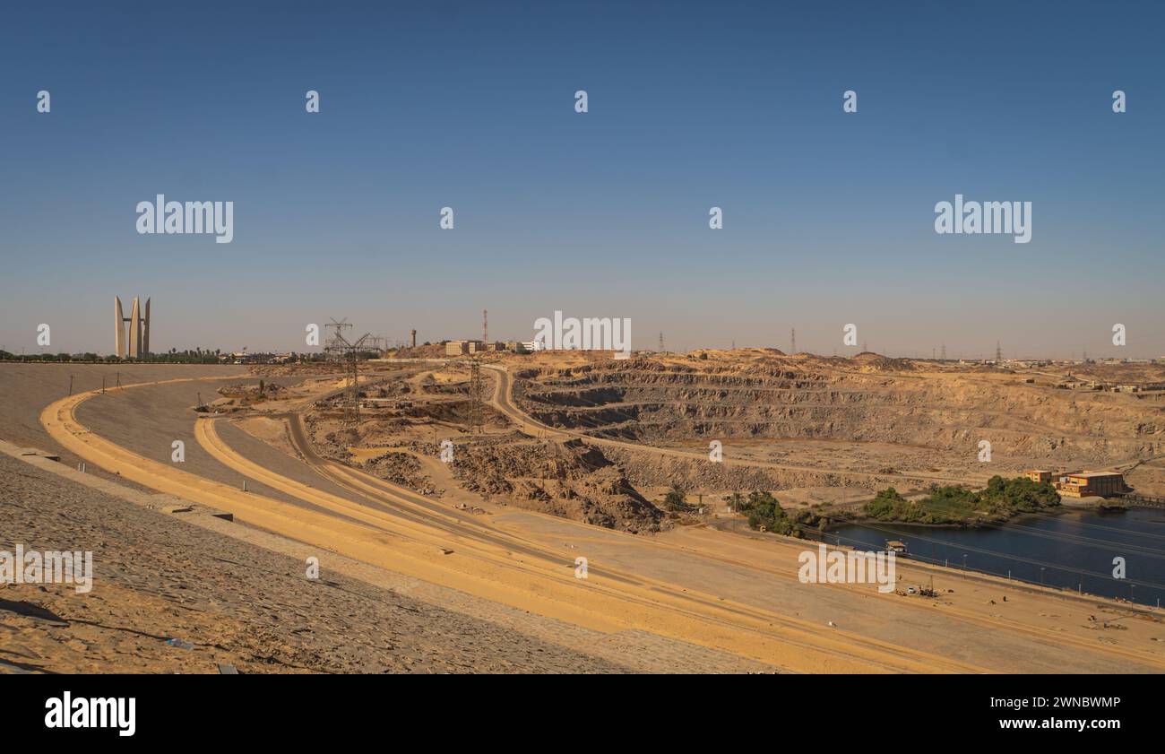 La diga di Assuan domina il fiume Nilo ad Assuan, in Egitto, e utilizza il potere del fiume per una varietà di cause sociali ed economiche con il monumento Foto Stock