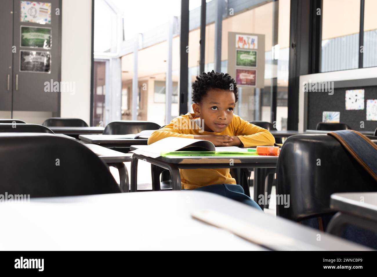 Ragazzo afroamericano siede in una classe scolastica, la sua espressione pensiva, con spazio di copia Foto Stock