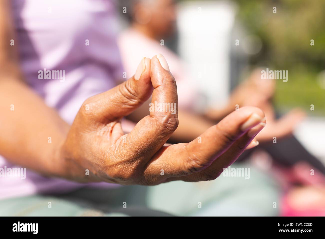 Una donna afroamericana senior pratica yoga in un ambiente soleggiato all'aperto Foto Stock