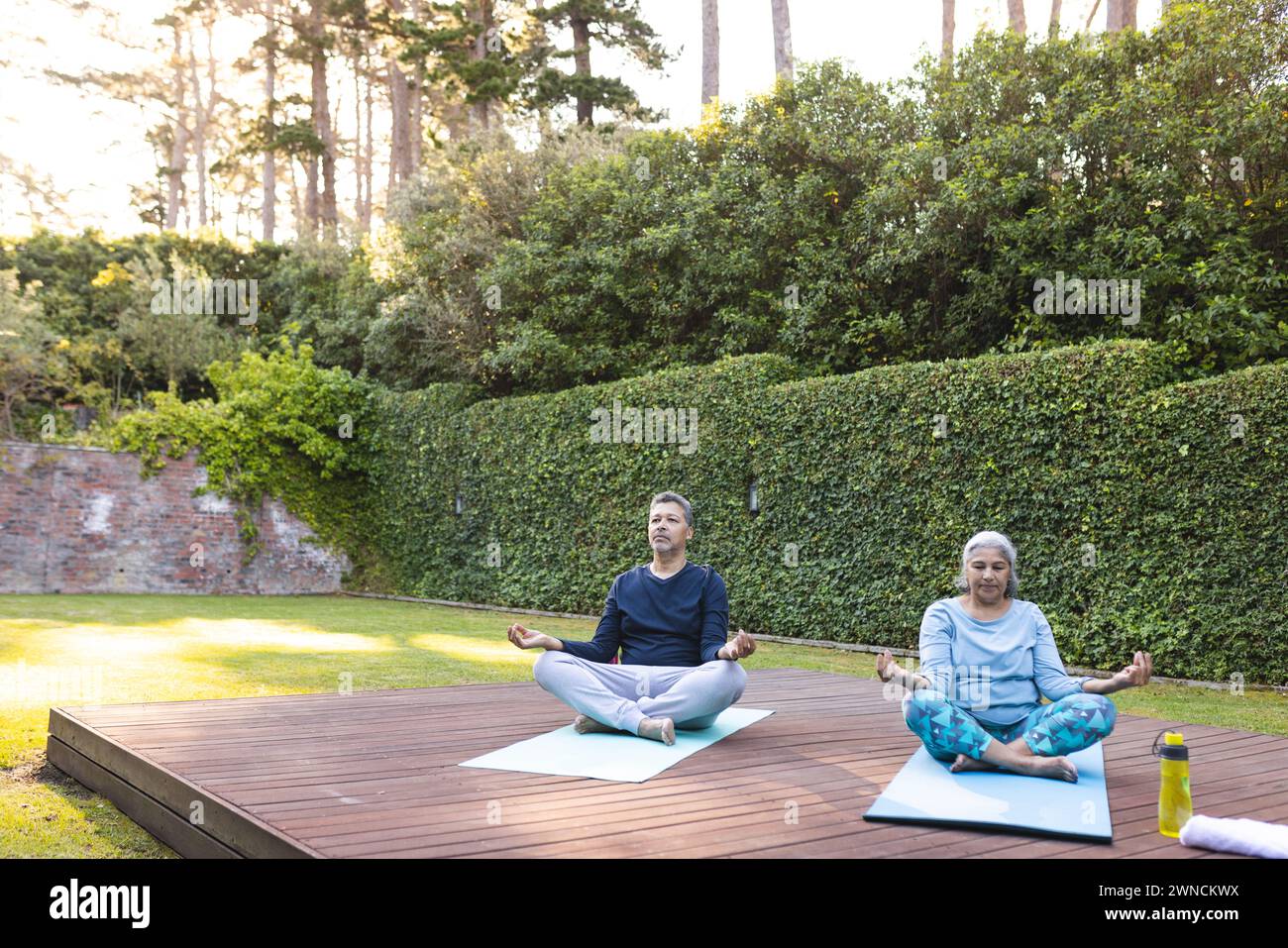 Donna birazziale senior e uomo birazziale praticano yoga all'aperto con spazio per copiare a casa Foto Stock