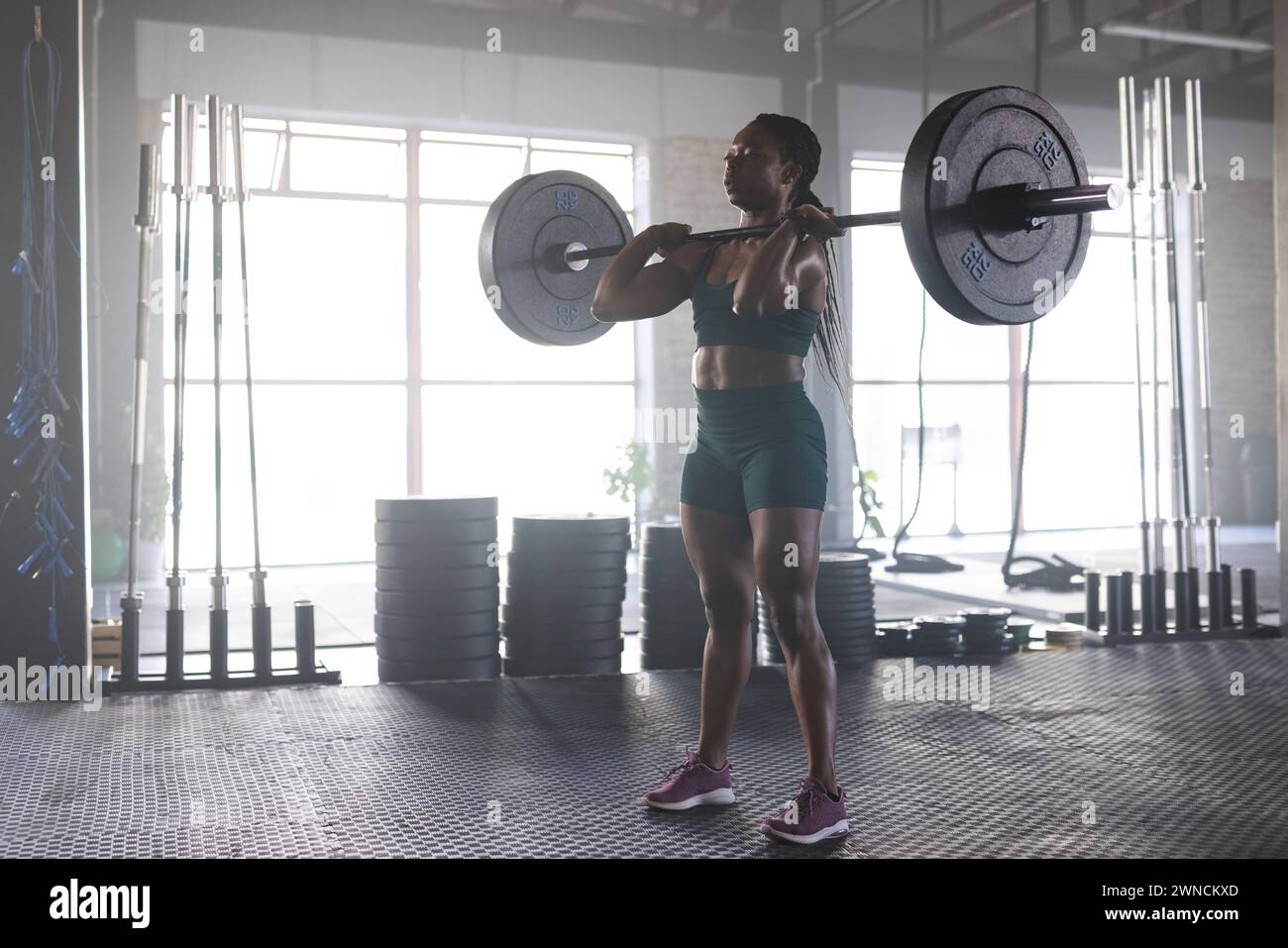 Donna birazziale in costume verde solleva pesi, incarnando forza e concentrazione. Foto Stock