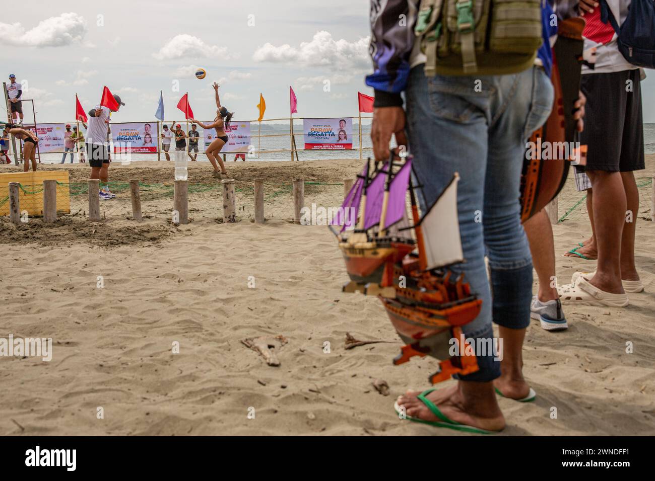 Iloilo City, Filippine. 2 marzo 2024. Un venditore di galeoni in miniatura visto assistere a una partita competitiva di Beach volley come parte della celebrazione del Paraw Regatta Festival a Iloilo City, Filippine. Il Paraw Regatta Festival è il più antico evento di artigianato tradizionale in Asia e ha come principale evento una gara di barche a vela, che lo rende il più grande evento velico delle Filippine. Credito: SOPA Images Limited/Alamy Live News Foto Stock