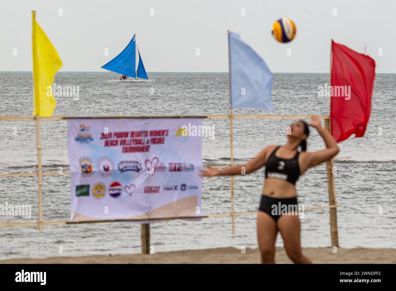 Iloilo City, Filippine. 2 marzo 2024. Una barca a vela è vista come un giocatore gareggia durante una partita competitiva di Beach volley come parte della celebrazione del Paraw Regatta Festival a Iloilo City, Filippine. Il Paraw Regatta Festival è il più antico evento di artigianato tradizionale in Asia e ha come principale evento una gara di barche a vela, che lo rende il più grande evento velico delle Filippine. Credito: SOPA Images Limited/Alamy Live News Foto Stock