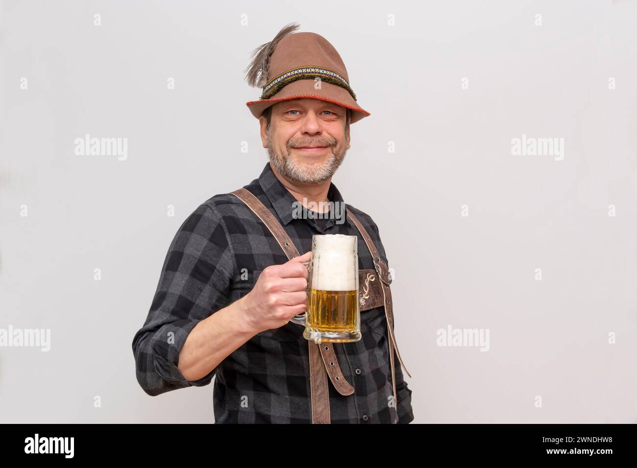 L'anziano barbuto in cappello vuole bere un bicchiere di birra con la schiuma, festival della birra in Austria e Germania. Foto Stock