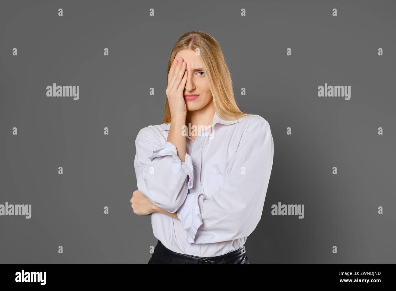 Ritratto di una giovane donna stanca e sgombra che copre un occhio con il palmo Foto Stock