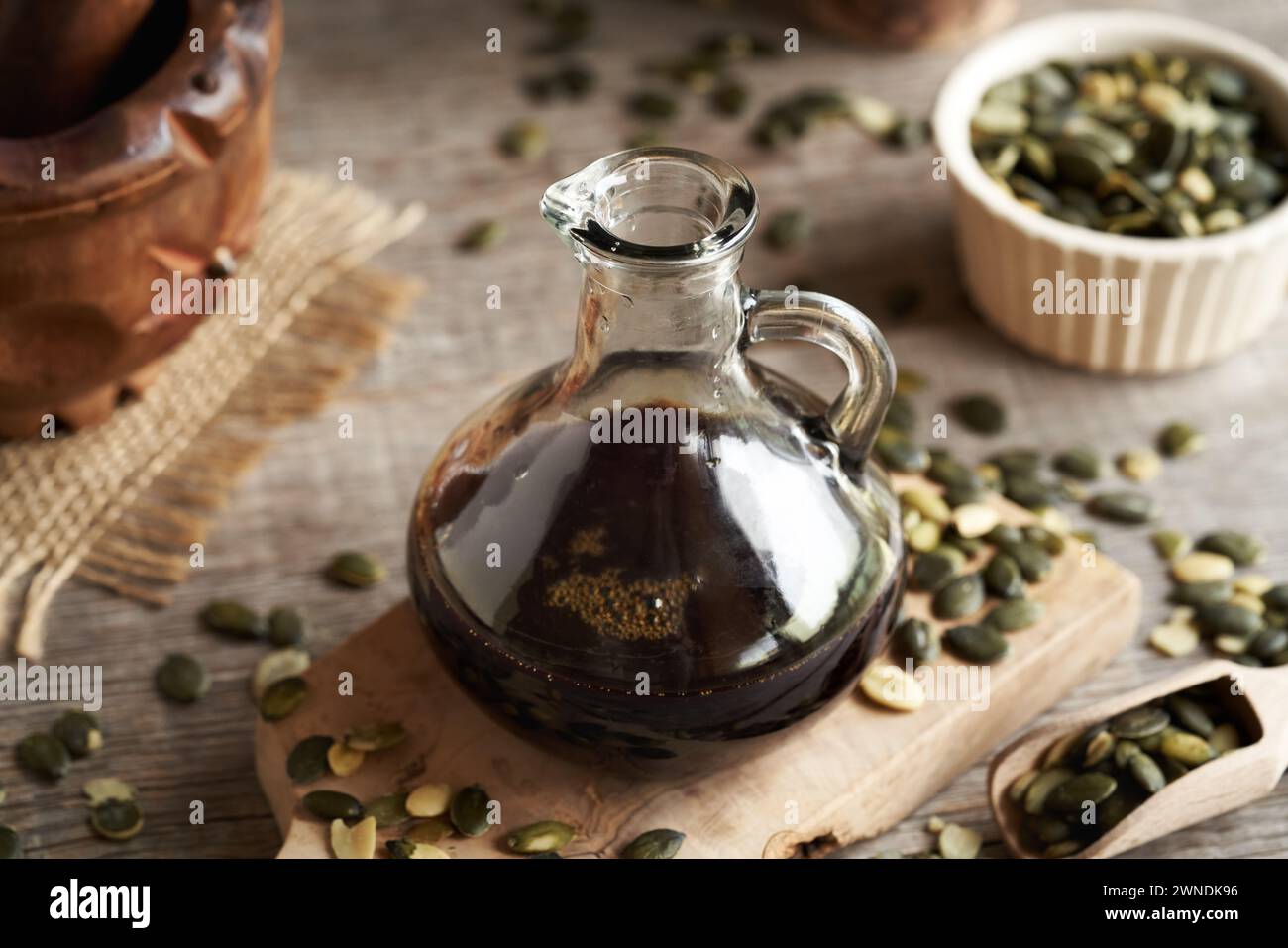 Olio di semi di zucca scuro in una bottiglia di vetro su un tavolo Foto Stock