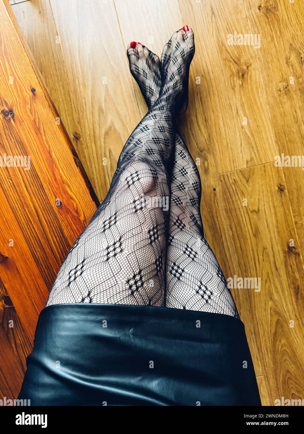 Vista dall'alto di una donna a gambe incrociate che indossa tights con motivo Foto Stock Vista dall'alto di una donna a gambe incrociate che indossa tights con motivo Foto Stock