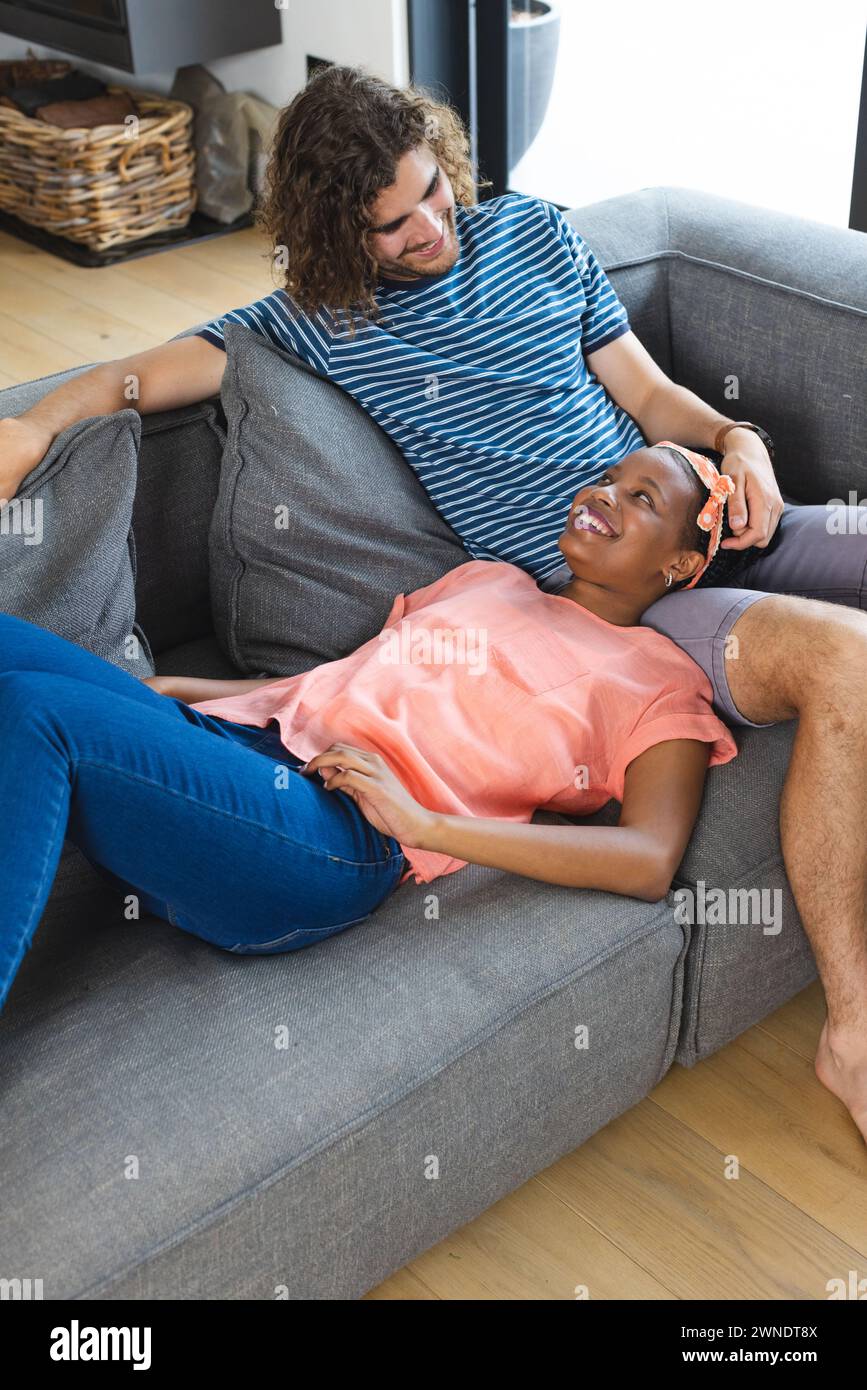 La coppia condivide un momento accogliente sul divano, esprimendo gioia e affetto. Foto Stock