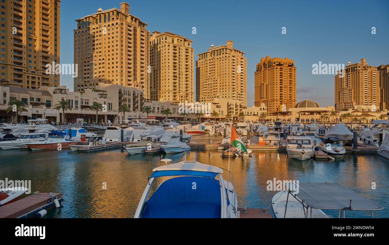 Porto Arabia Marina nella perla, Doha, Qatar, mostra lussuosi yacht e barche attraccate al porticciolo con edifici residenziali sullo sfondo. Foto Stock