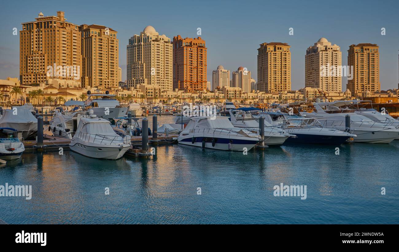 Porto Arabia Marina nella perla, Doha, Qatar, mostra lussuosi yacht e barche attraccate al porticciolo con edifici residenziali sullo sfondo. Foto Stock