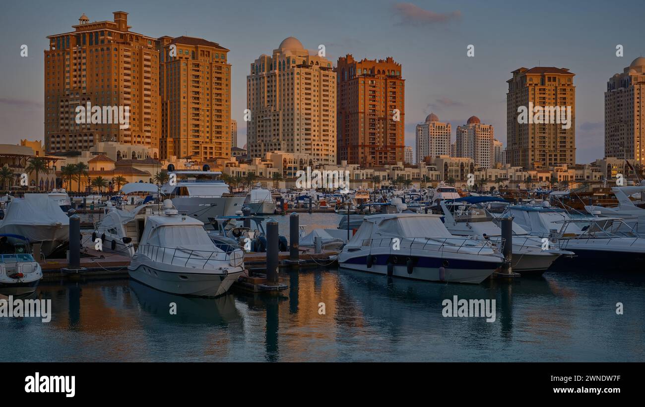 Porto Arabia Marina nella perla, Doha, Qatar, mostra lussuosi yacht e barche attraccate al porticciolo con edifici residenziali sullo sfondo. Foto Stock