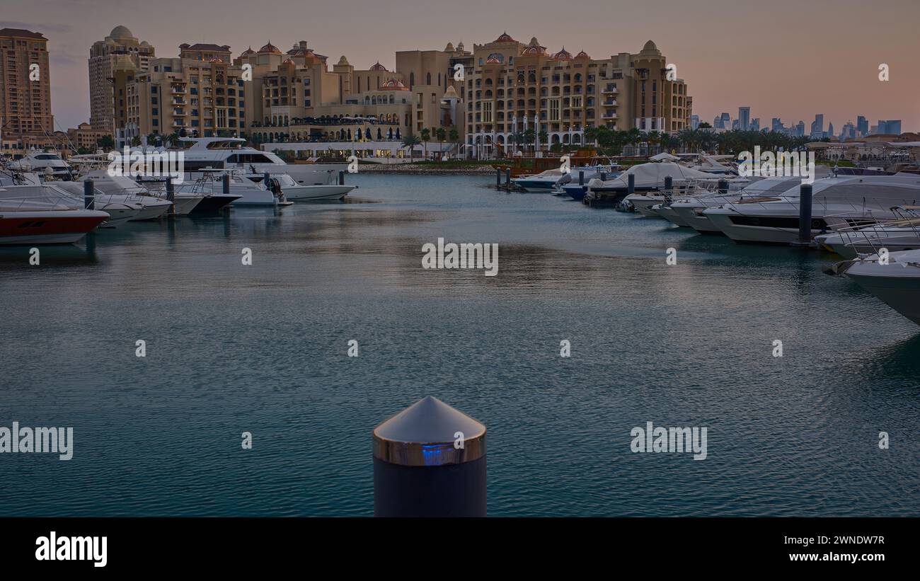 Porto Arabia Marina nella perla, Doha, Qatar, mostra lussuosi yacht e barche attraccate al porticciolo con edifici residenziali sullo sfondo. Foto Stock