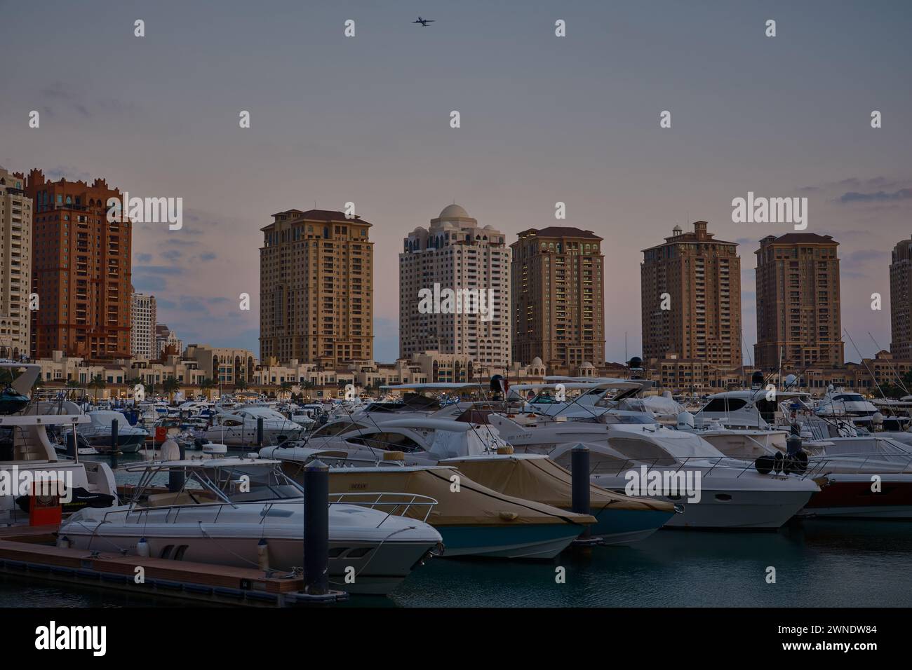 Porto Arabia Marina nella perla, Doha, Qatar, mostra lussuosi yacht e barche attraccate al porticciolo con edifici residenziali sullo sfondo. Foto Stock