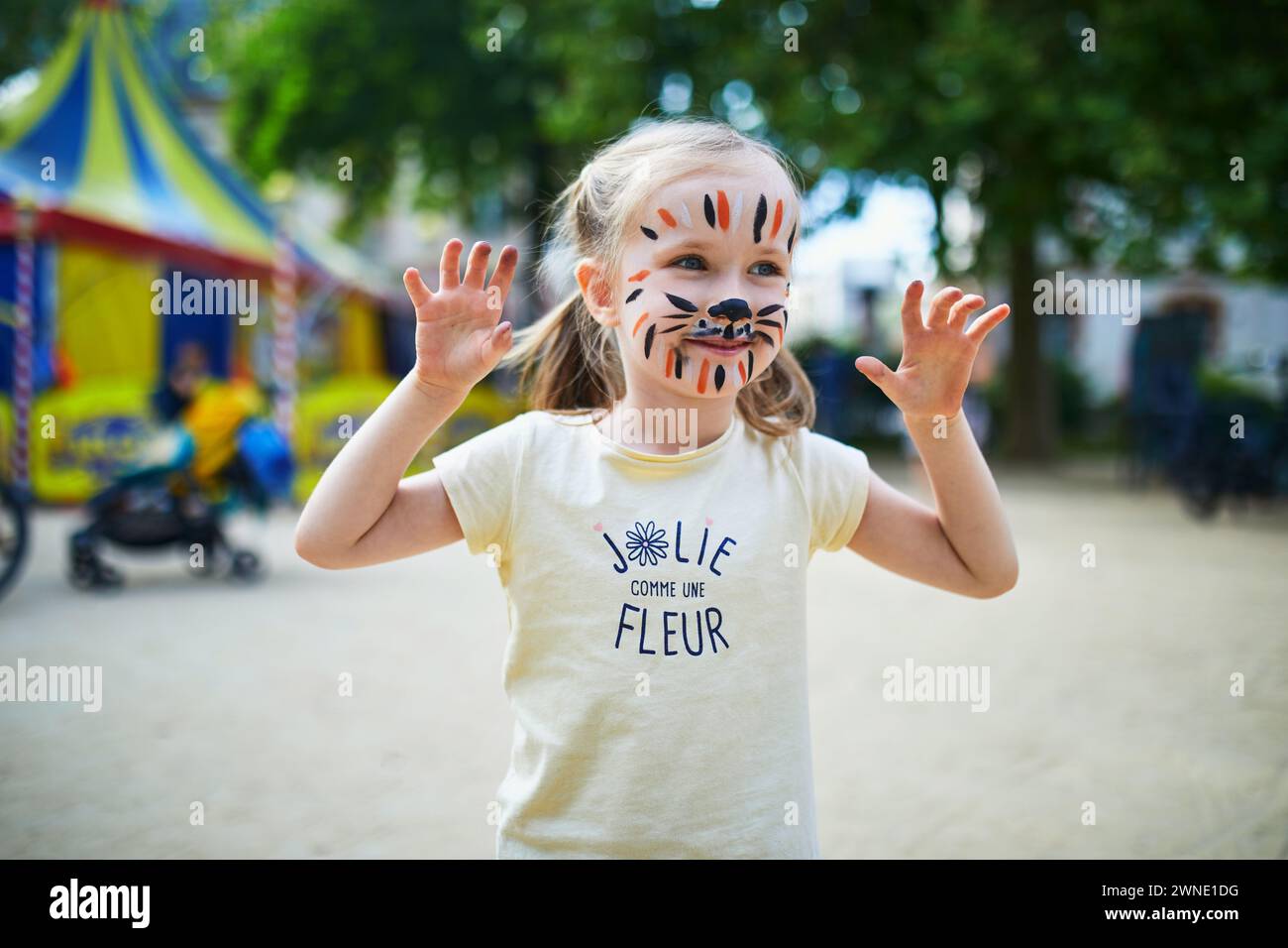 Bambina prescolare con il viso tigre che dipinge all'aperto. I bambini dipingono il viso. Attività creative per bambini Foto Stock