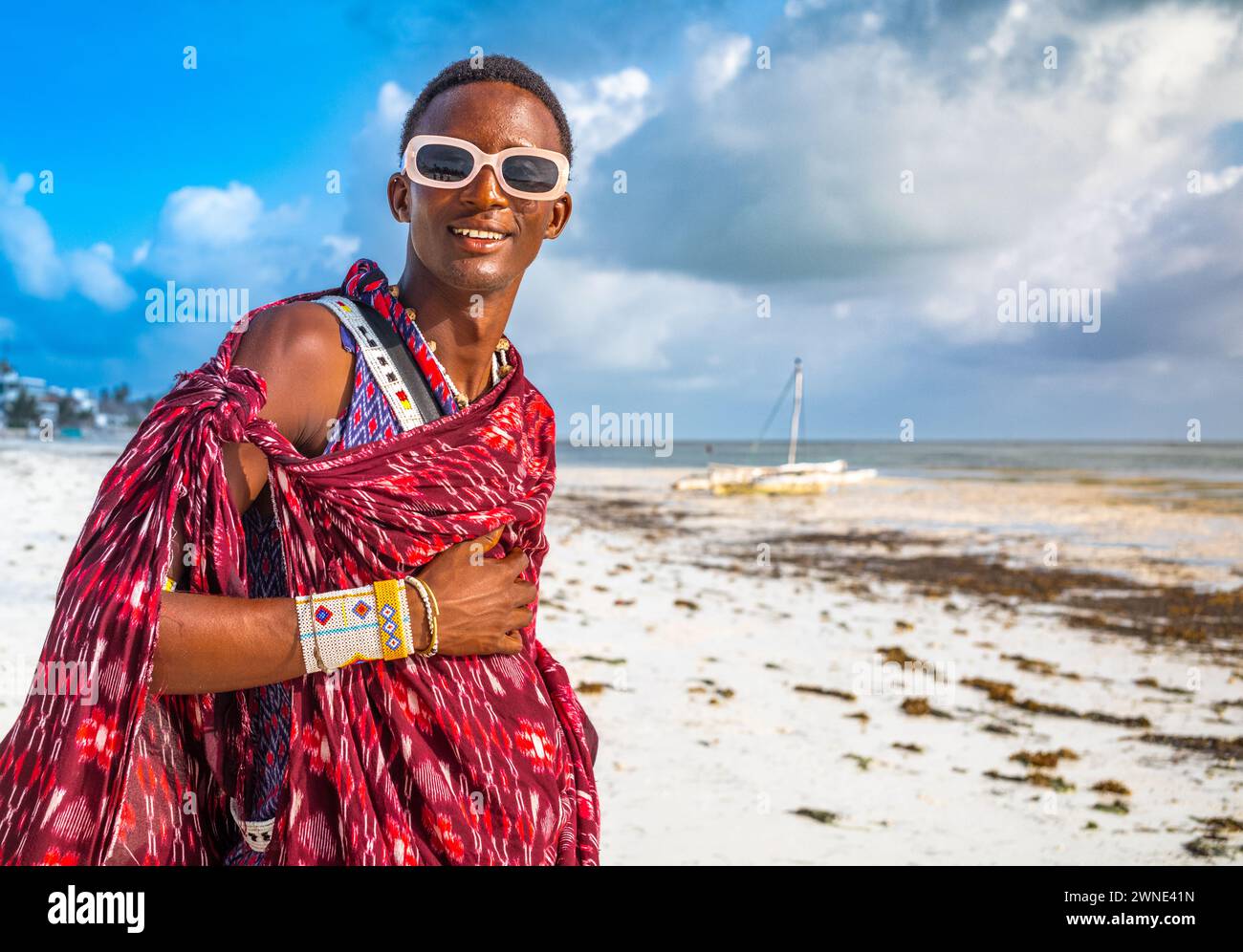 Un giovane guerriero Maasai in un tradizionale shuka sulla spiaggia di Jambiani, Zanzibar, Tanzania Foto Stock