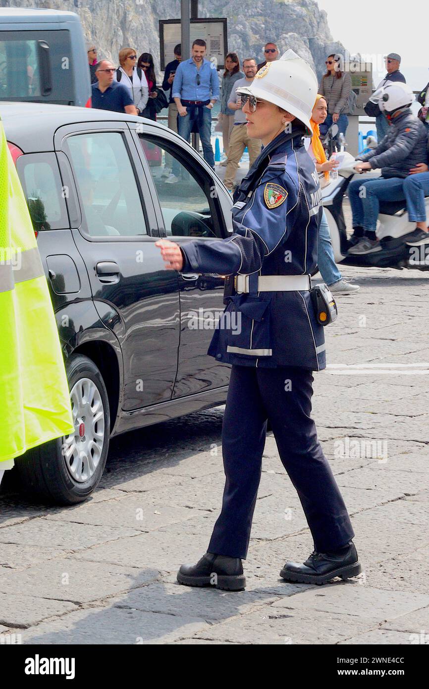 A causa della mancanza di posti auto, una poliziotta italiana dirige il traffico alla rotatoria sul lungomare del porto di Amalfi durante un affollato Bank Holiday. Foto Stock