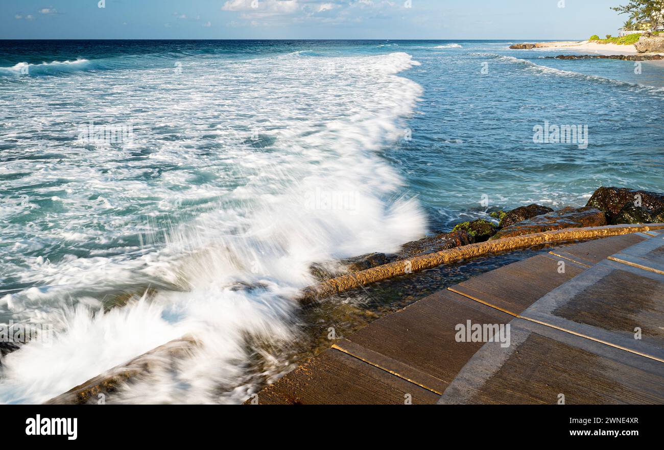 Mare invitante e cristallino e surf schiumoso che lambiscono dolcemente sulle splendide sabbie morbide di Rockley Beach, Barbados. Foto Stock