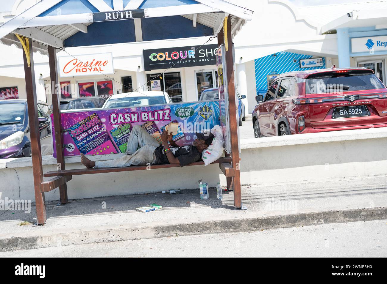 Un uomo che si rilassa e legge il suo libro in un rifugio per autobus a Bridgetown, Barbados Foto Stock