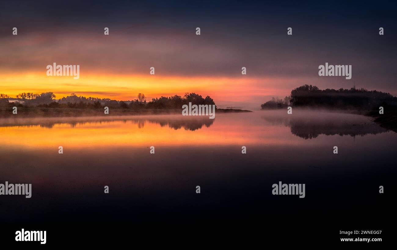 Pittoresco tramonto riflesso nelle acque calme accanto a un paesaggio nebbioso, il Reno meno Danubio RMD Canal Bamberga Foto Stock