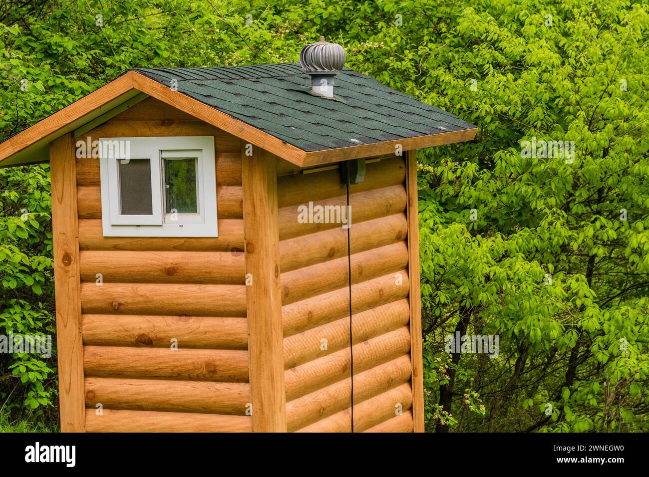 Servizi igienici pubblici costruiti per sembrare una piccola capanna di legno situata in un parco boschivo con lussureggiante vegetazione da qualche parte in Corea del Sud Foto Stock