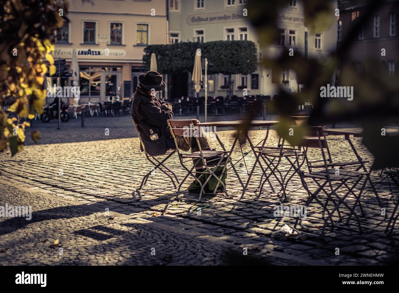 Una persona siede da sola ad un tavolo da caffe', leggendo rilassata nell'atmosfera autunnale, sulle strade di Weimar Foto Stock