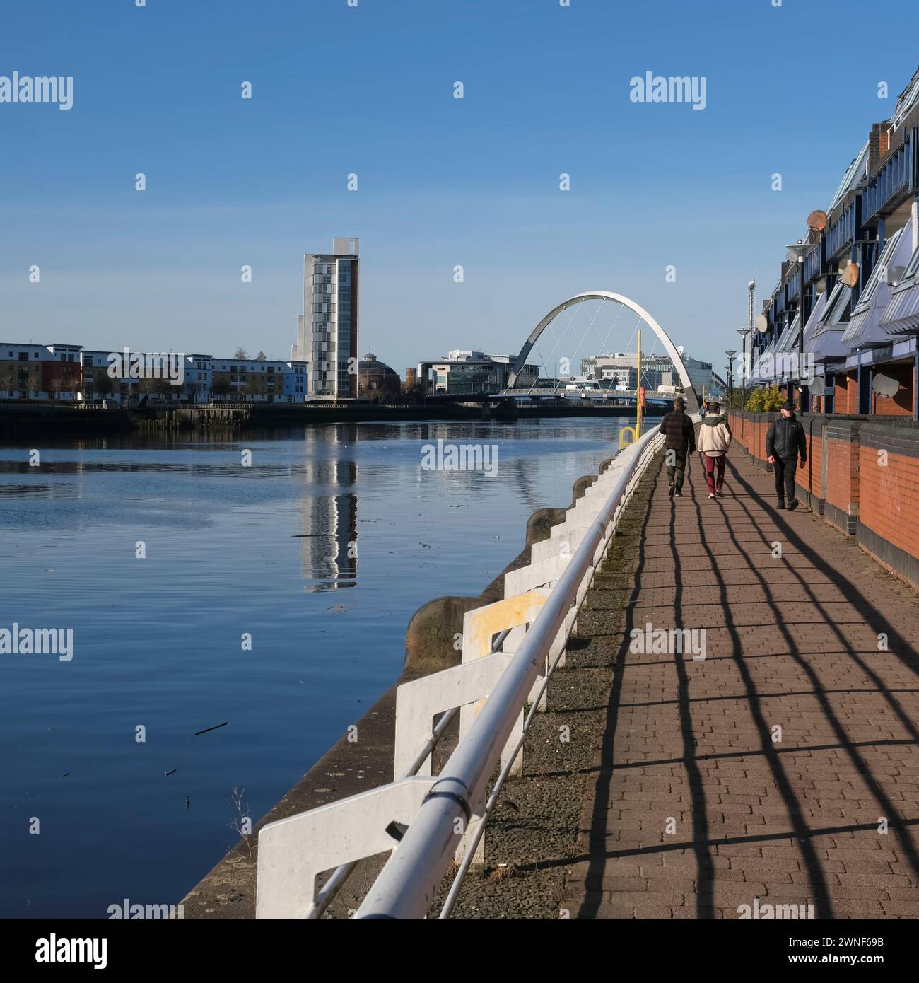 La gente cammina lungo la banchina sul fiume Clyde verso il ponte Squinty, Glasgow, Scozia, Regno Unito Foto Stock