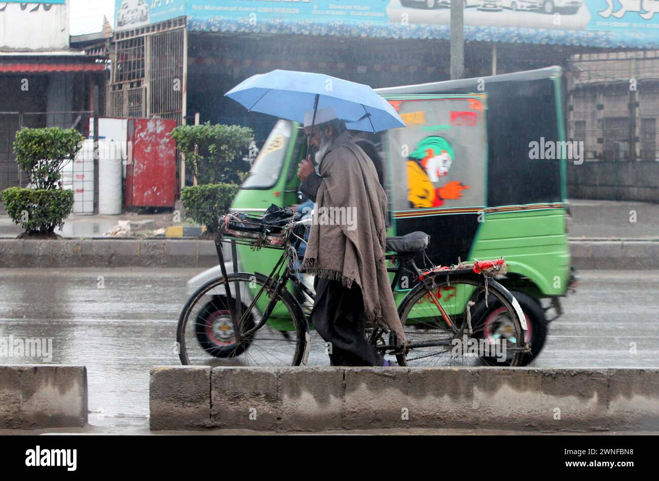 Hyderabad, Pakistan. 2 marzo 2024. Il pendolare tiene l'ombrello sopra la testa per salvarsi dalla pioggia e si sposta verso la loro destinazione durante la stagione invernale, a Peshawar sabato 2 marzo 2024. Crediti: Pakistan Press International (PPI)/Alamy Live News Foto Stock