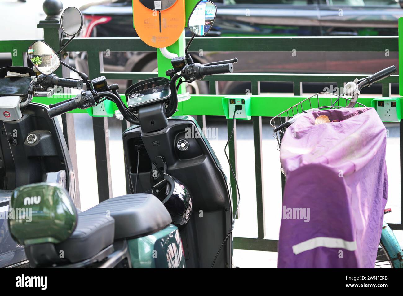 GUANGZHOU, CINA - 22 febbraio 2024: Scooter elettrico con stazione di ricarica su una strada cittadina Foto Stock