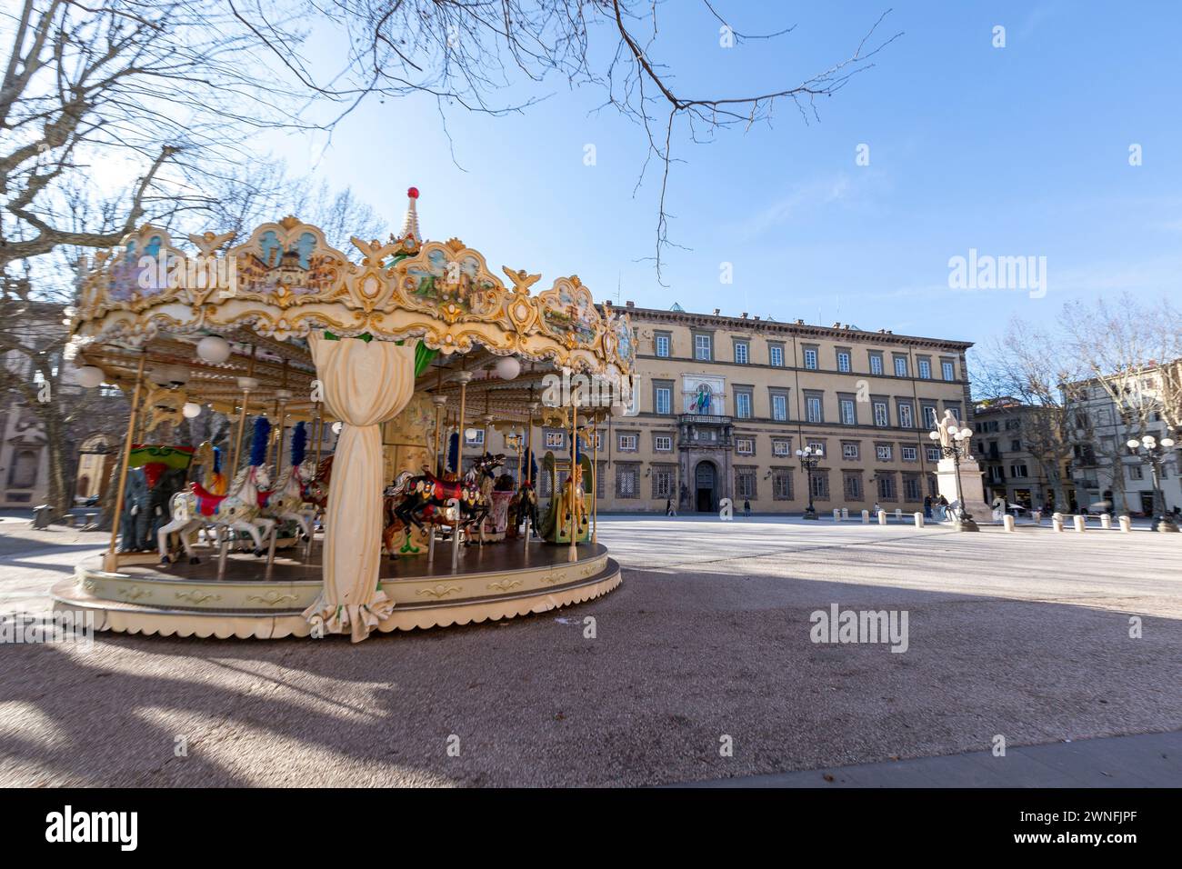 Colorata giostra di fronte al Palazzo Ducale in Piazza Napoleone nel centro storico della città medievale di Lucca, Italia Foto Stock